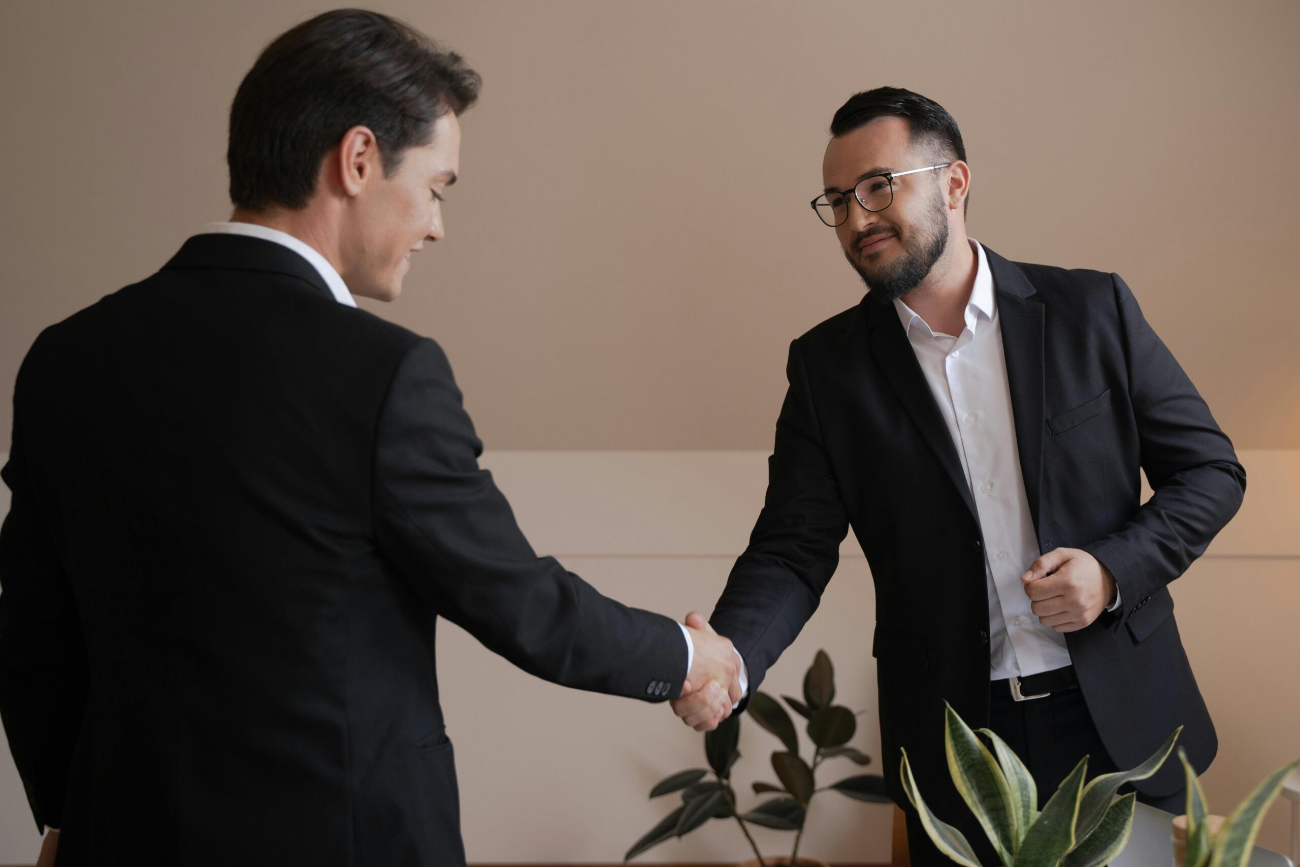 Two businessmen shaking hands in an office, symbolizing agreement and cooperation. Investment broker